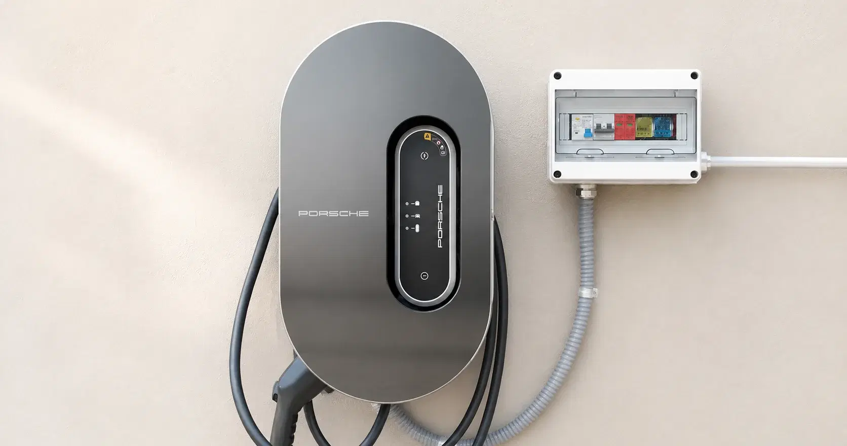 Cargador para auto eléctrico montado en un muro, junto a su caja de protecciones eléctricas.